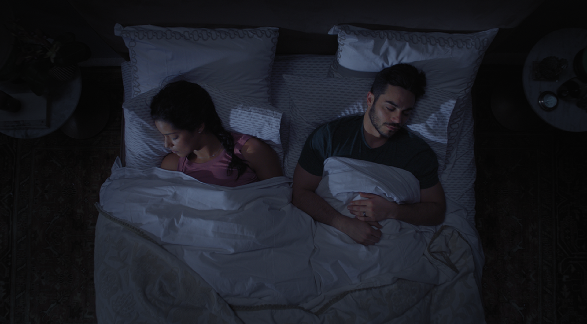 Top-down view of aman and woman sleeping soundly in bed