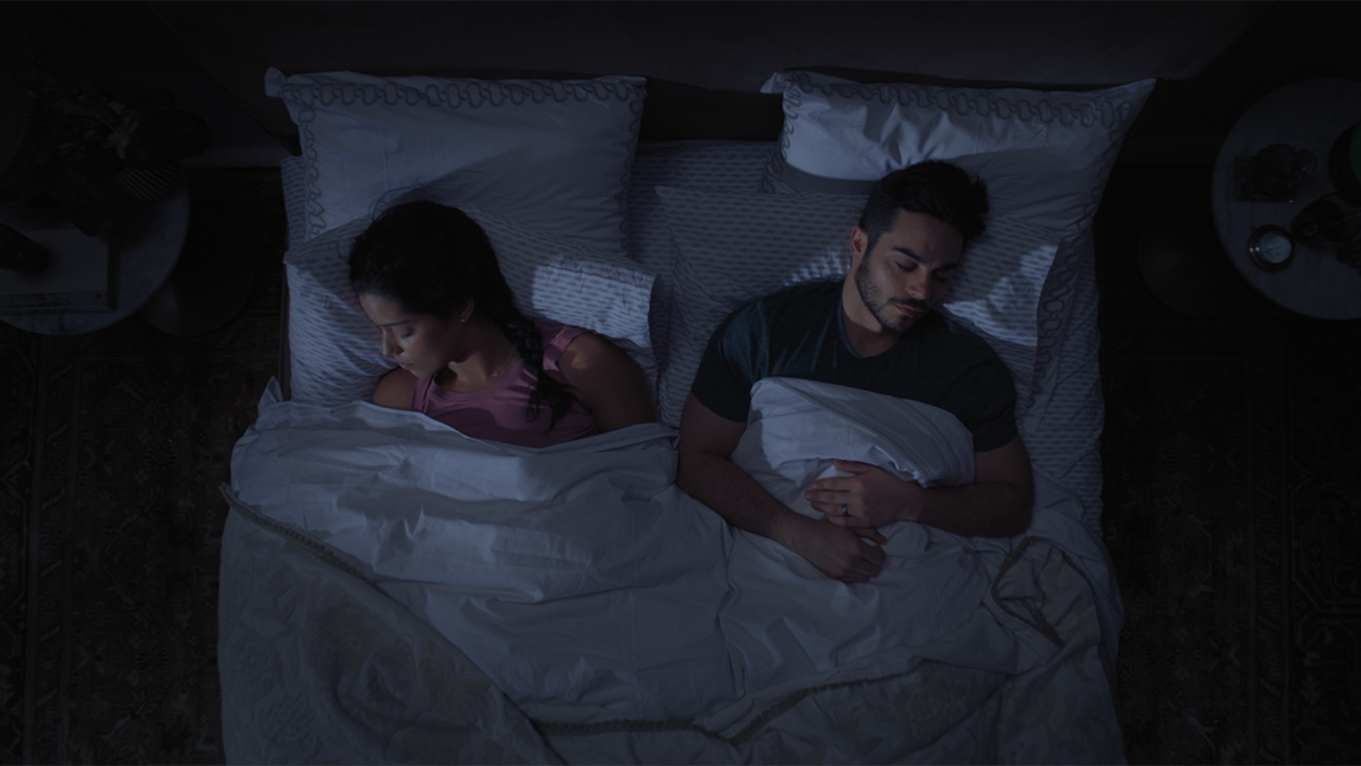 Top-down view of aman and woman sleeping soundly in bed